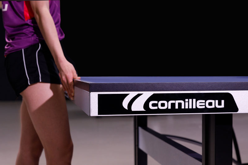 main qui range une balle dans le flanc d'une table de ping pong Cornilleau 500 indoor