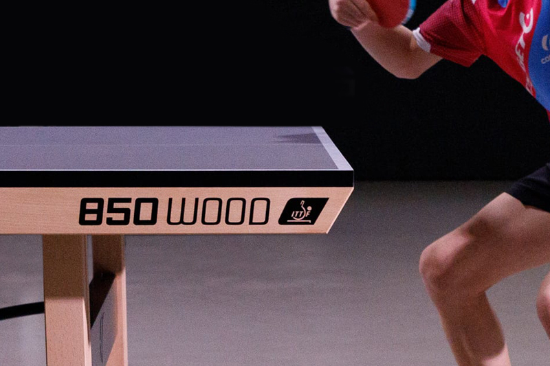main qui range une balle dans le flanc d'une table de ping pong Cornilleau 500 indoor